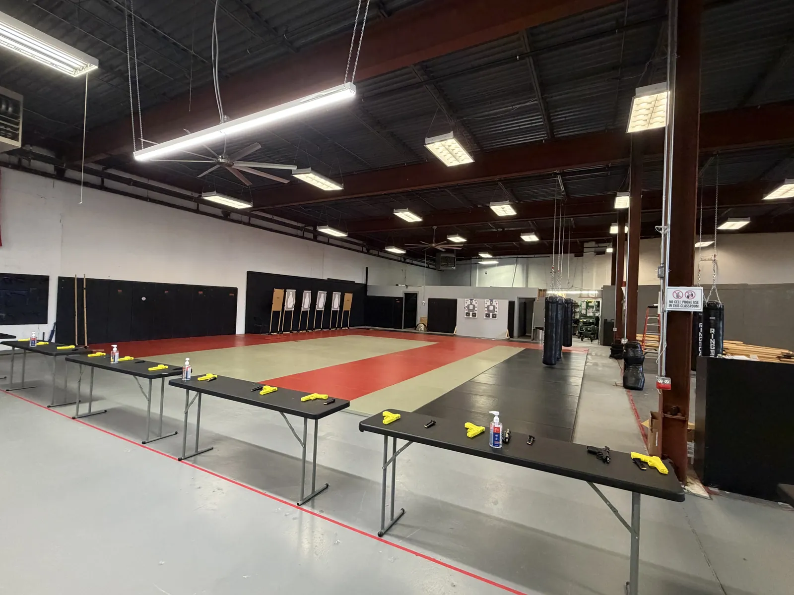 The Boston Firearms classroom and training floor: tables set with training pistols, mats, and target stands along the wall.
