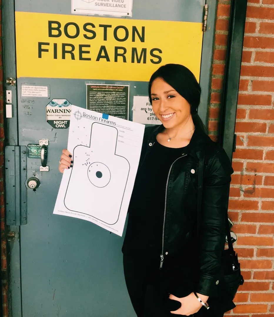 A smiling student outside the Boston Firearms door in Everett, holding the target she just shot