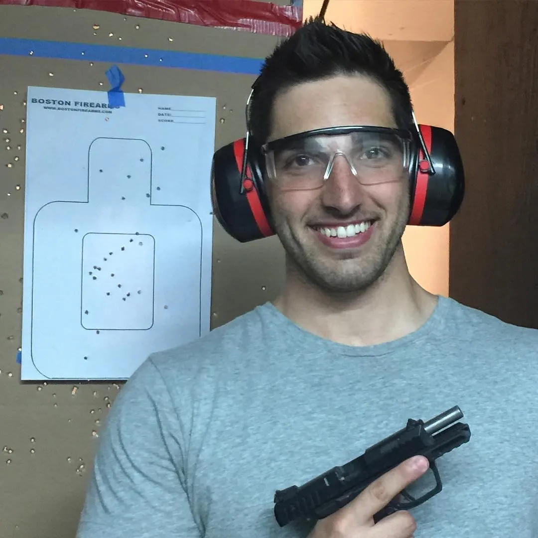 A first-time shooter in ear and eye protection at the Boston Firearms range with the target he has just shot.